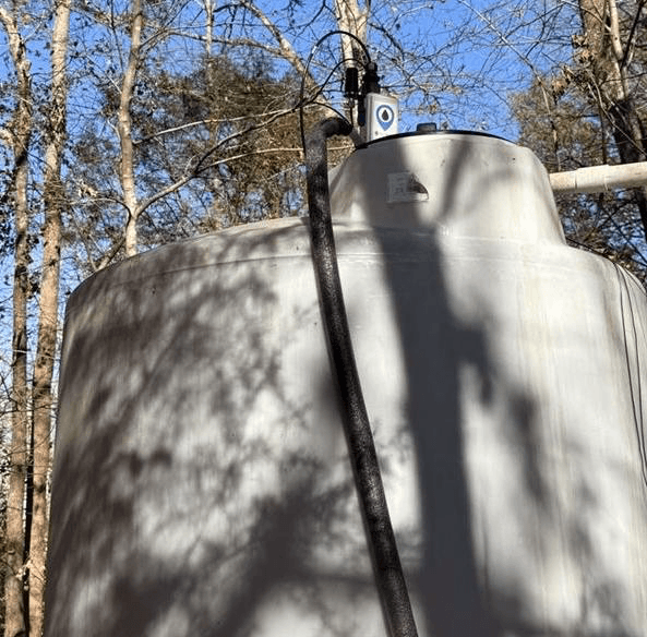 WellAware Scout device mounted on top of a large white water storage tank in a field setting.